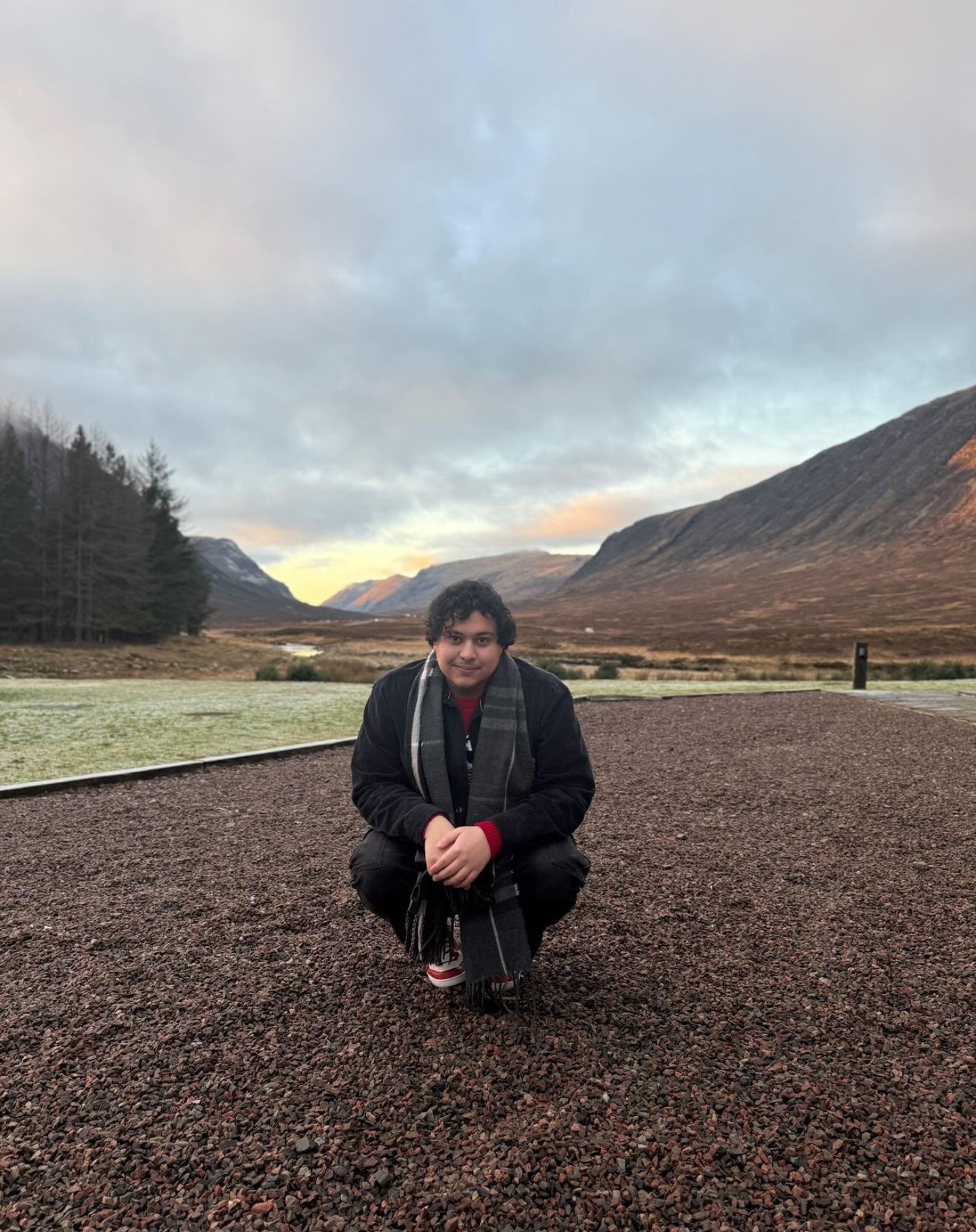 Samuels crouching on a gravel road with mountains behind