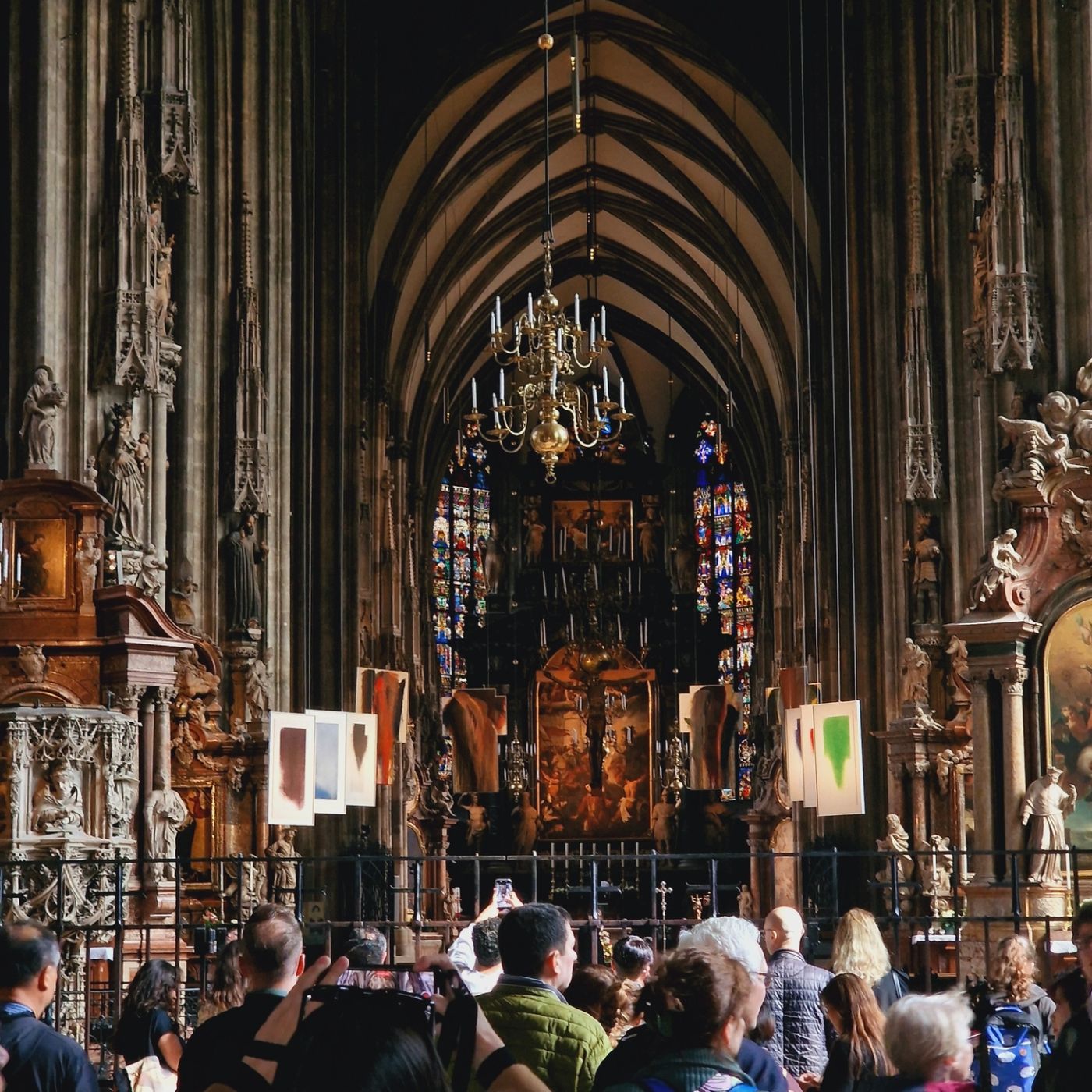 Gothic cathedral nave with stained glass and a crowd of visitors